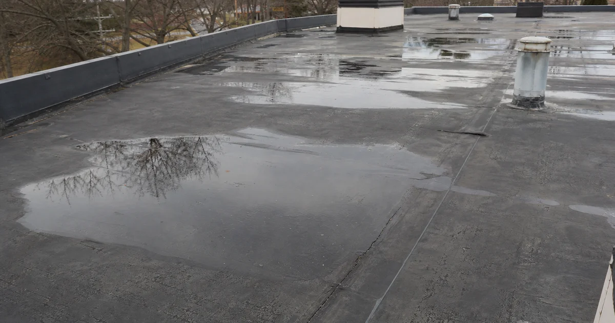 Aged EPDM commercial flat roof showing seam separation and ponding water
