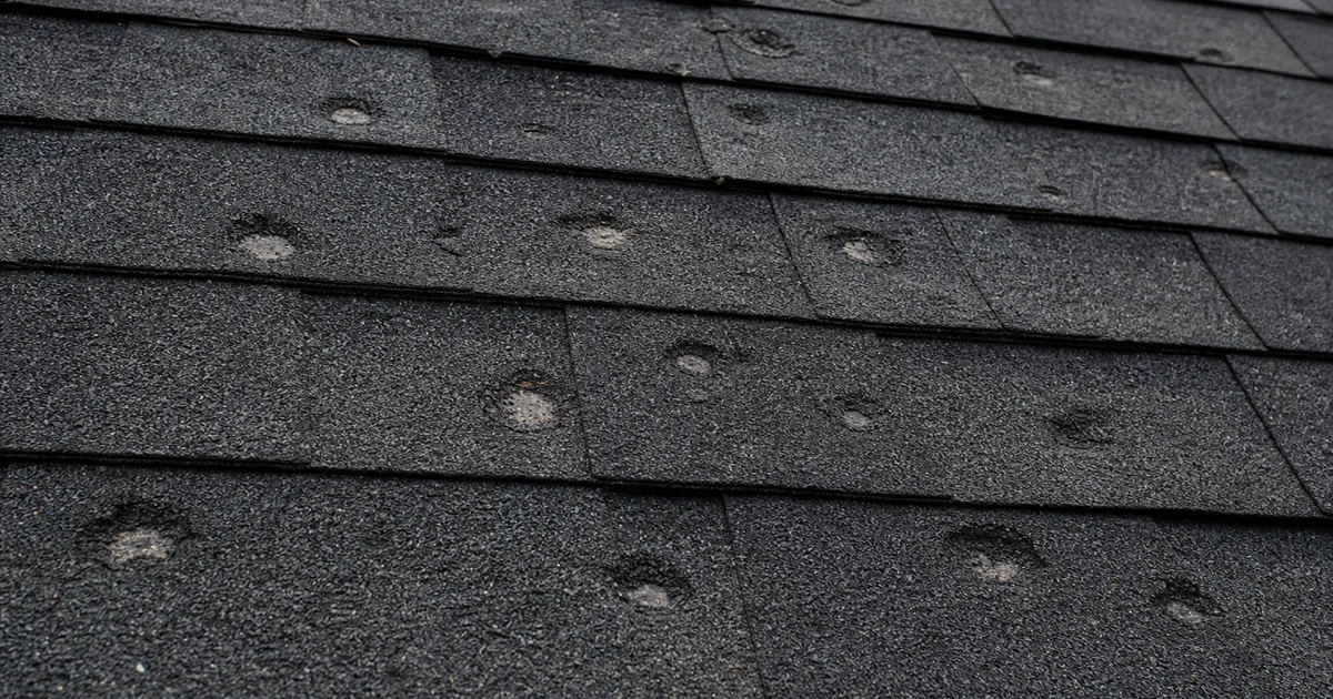 Hail bruising marks on architectural asphalt shingles, close-up